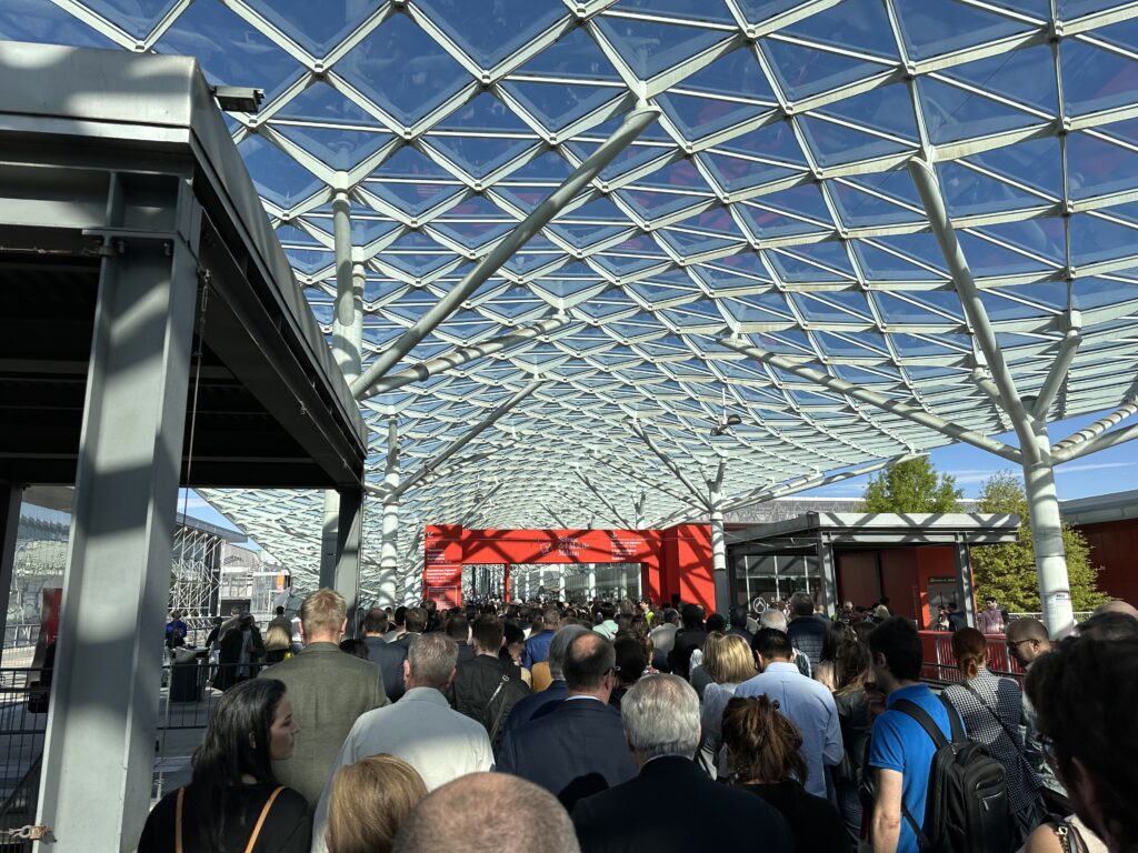 Folla di persone in fila sotto la copertura in vetro dell’ingresso di Fieramilano Rho per il Salone del Mobile 2024.