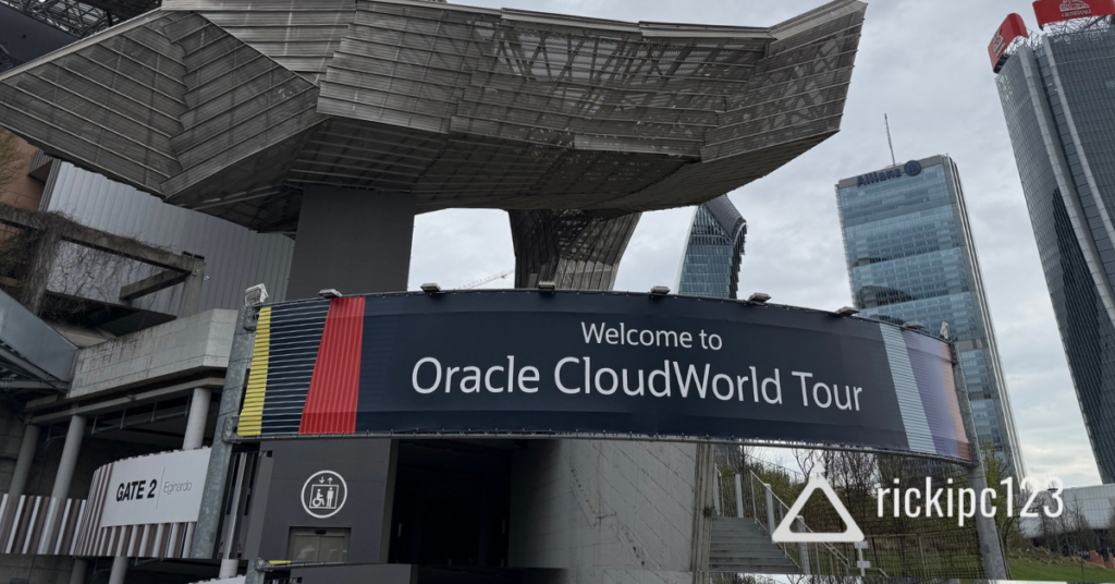 Ingresso del MiCo Milano Convention Centre con un grande banner che accoglie i partecipanti all’Oracle CloudWorld Tour, con i grattacieli di Milano sullo sfondo.