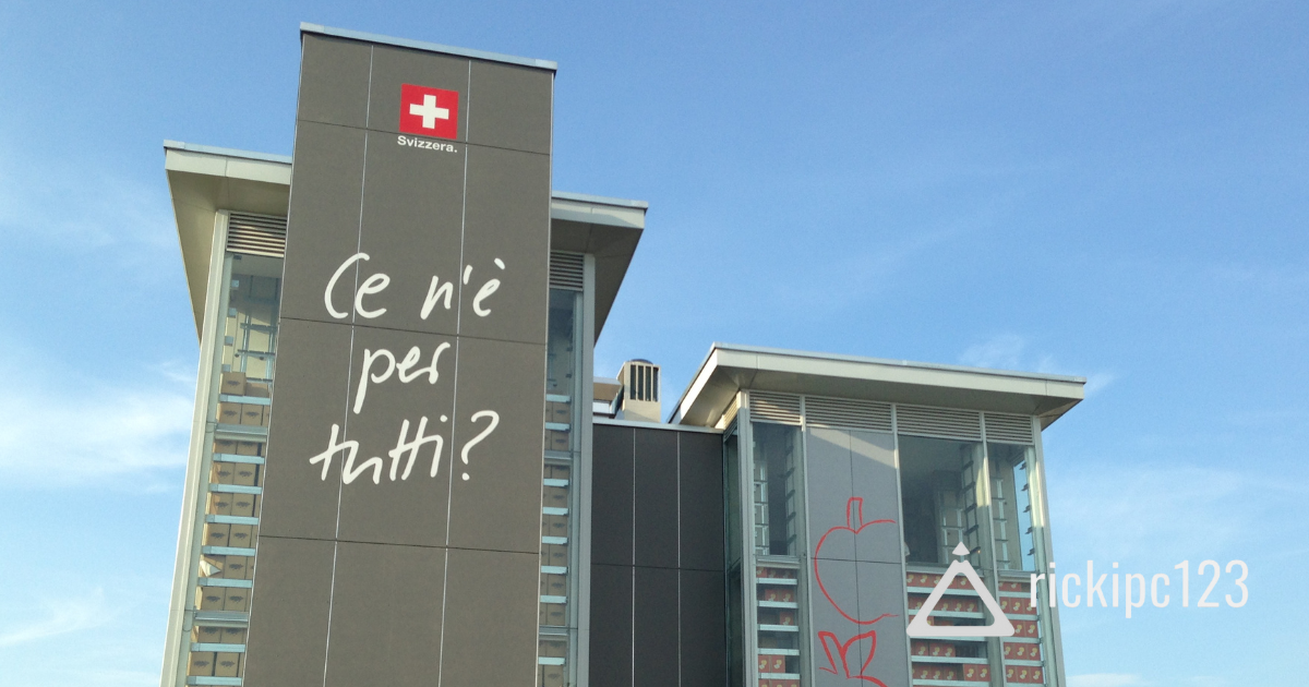 Struttura a torri del padiglione Svizzera all’Expo 2015, con le scritte “Ce n’è per tutti?” e le scorte di mele secche e acqua visibili