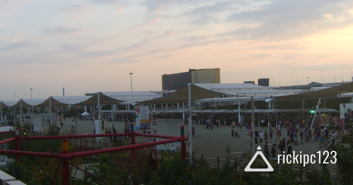 Vista panoramica dell’ingresso del Decumano di Expo 2015 con padiglioni e visitatori, al tramonto